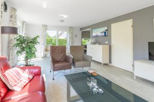 Una sala de estar con un sofá rojo y una mesa. en Villapark Kamperfoelie 77, en De Koog