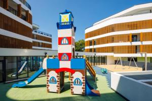 a playground in front of a building with a lighthouse at Baltic Waves Resort by PI Apartments - Official Operator in Międzyzdroje +82 photos