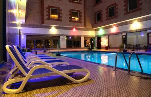 una piscina con sedie a sdraio accanto a un edificio di Ramee Guestline Hotel a Mascate