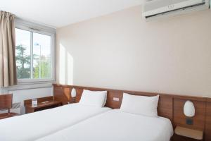 pokój hotelowy z dwoma łóżkami i oknem w obiekcie Brit Hotel Toulouse Colomiers – L’Esplanade w mieście Colomiers