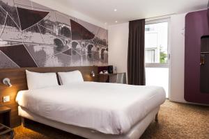 Pokój hotelowy z dużym białym łóżkiem i oknem w obiekcie Brit Hotel Toulouse Colomiers – L’Esplanade w mieście Colomiers