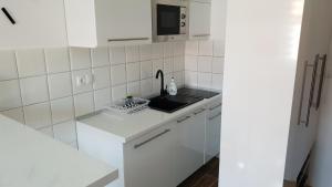 a white kitchen with a sink and a microwave at Apartman Savic 1 in Bijeljina