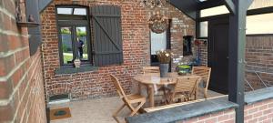 a patio with a wooden table and chairs at Les roses d'Olga in Aubechies