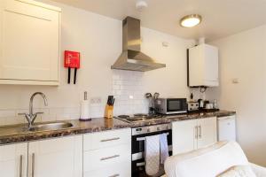 a kitchen with white cabinets and a sink at Westminster College Cottages, Cambridge in Cambridge