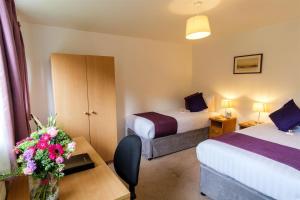 a hotel room with two beds and a table with flowers at Westminster College Cottages, Cambridge in Cambridge