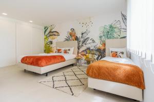 two beds in a bedroom with a tropical wallpaper at Diamond Villa, luxury house with private pool in Lourinhã