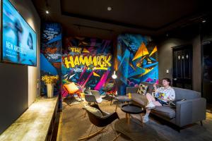 ホーチミン・シティにあるThe Hammock Hotel Fine Arts Museumの壁画のある部屋のソファに座る男