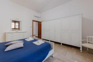 a white bedroom with a blue bed and a chair at Gate2-MarcoPoloAirport-2 camere da letto-Wifi-Netflix-15' da Venezia in Tessera +24 photos