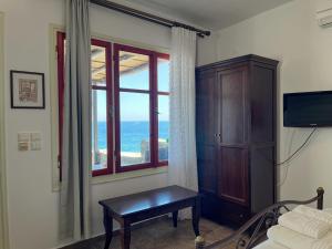 a bedroom with a bed and a window with the ocean at Niriides Studios & Apartments in Kithnos