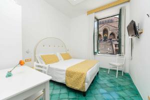 Una pequeña habitación con una cama y una ventana. en Albergo S. Andrea, en Amalfi