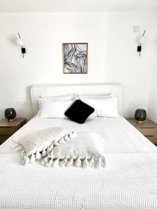 a white bed with a black and white blanket on it at Aptments4 - real estate solutions in Olbia