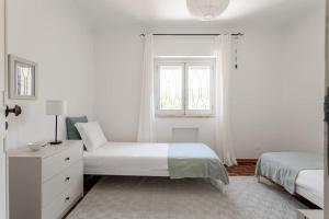 una camera da letto bianca con due letti e una finestra di Casa de São Pedro a Estoril