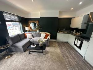 a living room with a gray couch and a kitchen at Casa Allerton in Liverpool