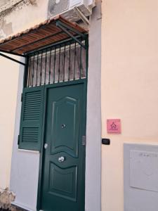 a green door on a building with a sign above it at La Petite Maison in Naples