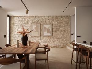 una sala da pranzo con tavolo e muro di mattoni di Esthesis Beachfront Villas, with Heated Pool, By ThinkVilla a Alykes