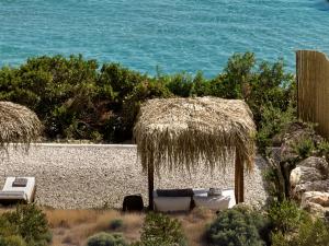 una spiaggia con due sedie e un ombrellone di paglia di Esthesis Beachfront Villas, with Heated Pool, By ThinkVilla a Alykes