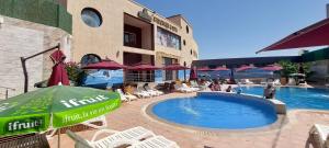 a pool with chairs and an umbrella next to a building at Atlantis Akbou in Akbou