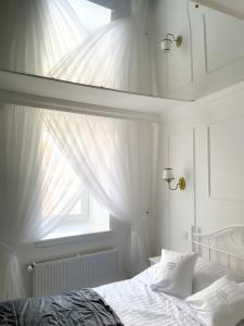 a bedroom with a bed with white curtains and a window at Podniebny Apartament Toruń in Toruń