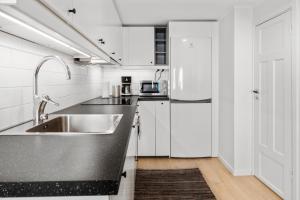 a white kitchen with a sink and a refrigerator at Magle Lilla Kyrkogata in Lund