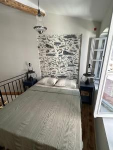 a bedroom with a large bed with a stone wall at Plomari Geometer House in Plomari