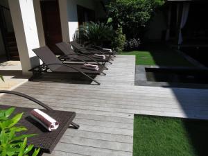 a row of chaise lounges on a wooden deck at Villa True Colors in Legian