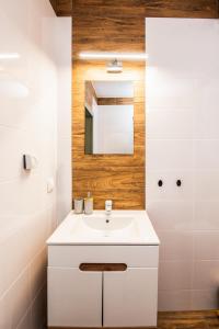 ein Badezimmer mit einem weißen Waschbecken und einem Spiegel in der Unterkunft Apartament przy plaży in Gąski