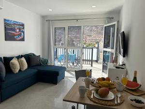 Una sala de estar con un sofá azul y una mesa. en NORAY Playa de Mogán, en Puerto de Mogán