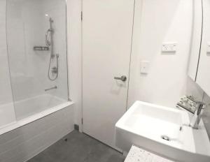 a white bathroom with a sink and a shower at Docklands Serenity in Melbourne
