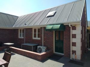 une maison en briques avec une télévision sur un patio dans l'établissement Hansen Park Guest Cottage, à Christchurch