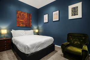 een slaapkamer met blauwe muren en een bed en een stoel bij Cosy 2-Bed with Modern Design & Alfresco Dining in Melbourne