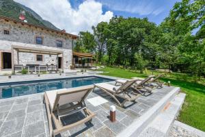 a group of lounge chairs next to a swimming pool at Villa Beatrice front lake in Rocca dʼAnfo