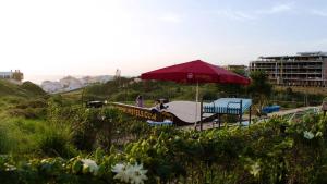 a picnic table with an umbrella and a boat at WOT Ericeira Surf Hostel in Ericeira