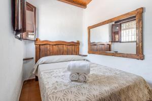 Un dormitorio con una cama con un espejo en la pared. en Casa Rural El Ventorrillo, en Morón de la Frontera