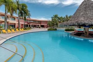a pool at the resort with chairs and a thatched roof at Hodelpa Garden Suites - All Inclusive in Juan Dolio