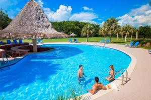 three people in a swimming pool at a resort at Hodelpa Garden Suites - All Inclusive in Juan Dolio
