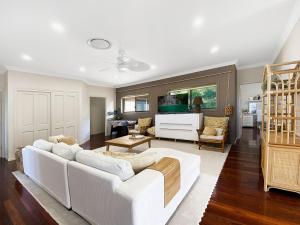 a living room with a white couch and a white piano at Family Entertainer with Pool - Luxury Holiday House in Lennox Head in Lennox Head
