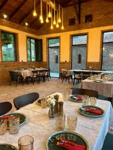 a dining room with tables and chairs and windows at Peradze Wine Cellar Vineyard Cottages in Khidistʼavi