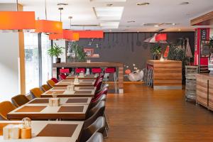 a dining room with a long line of tables and chairs at Ibis Kaunas Centre in Kaunas