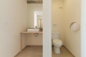 a bathroom with a white toilet and a mirror at WOT Ericeira Surf Hostel in Ericeira