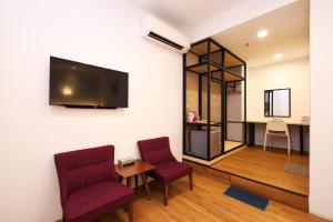 a living room with two chairs and a tv on a wall at Agape Hotel Selayang in Batu Caves