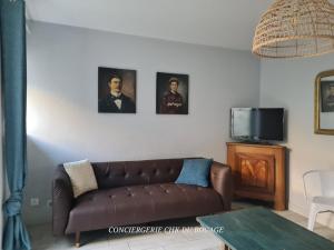 a living room with a brown couch and pictures on the wall at Logis Philiberte 3 chambres centre bourg des Epesses à 5min du Puy du Fou in Les Épesses