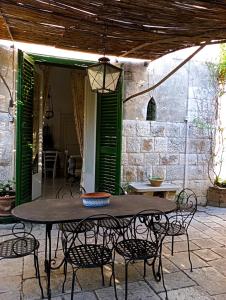 a table and chairs on a patio with green shutters at La Dimora di Donna Cecilia in Bari