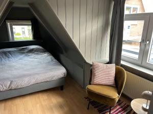 a bedroom with a bed and a chair and a window at Westerhuysje in Uitgeest
