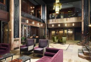 a lobby with chairs and tables and a chandelier at Hotel Phillips Kansas City, Curio Collection By Hilton in Kansas City