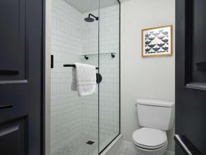 a bathroom with a toilet and a glass shower at Hotel Phillips Kansas City, Curio Collection By Hilton in Kansas City