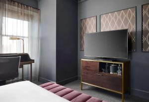 a living room with a flat screen tv on a dresser at Hotel Phillips Kansas City, Curio Collection By Hilton in Kansas City