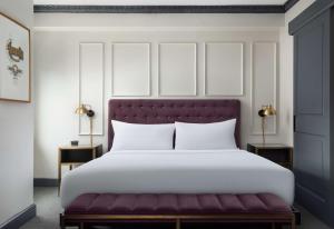 a bedroom with a large white bed with a purple bench at Hotel Phillips Kansas City, Curio Collection By Hilton in Kansas City
