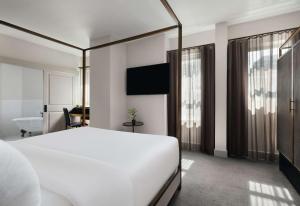 a bedroom with a white bed and a bathroom at Hotel Phillips Kansas City, Curio Collection By Hilton in Kansas City