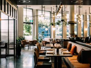查斯顿Hotel Chadstone Melbourne MGallery Collection的有桌椅和窗户的餐厅