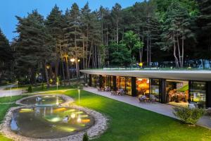 une maison avec un étang dans la cour dans l'établissement Bioli Wellness Resort, à Kojori